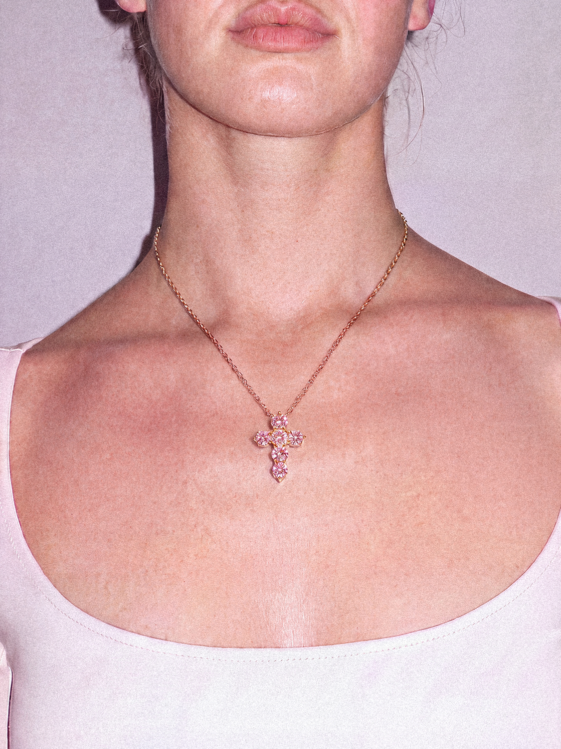 Model wearing the Bow Tie Lab Diamonds 1.55 ctw 7-stone Fancy Pink cross pendant necklace — round pink lab-grown diamonds on a delicate gold chain at the neckline.